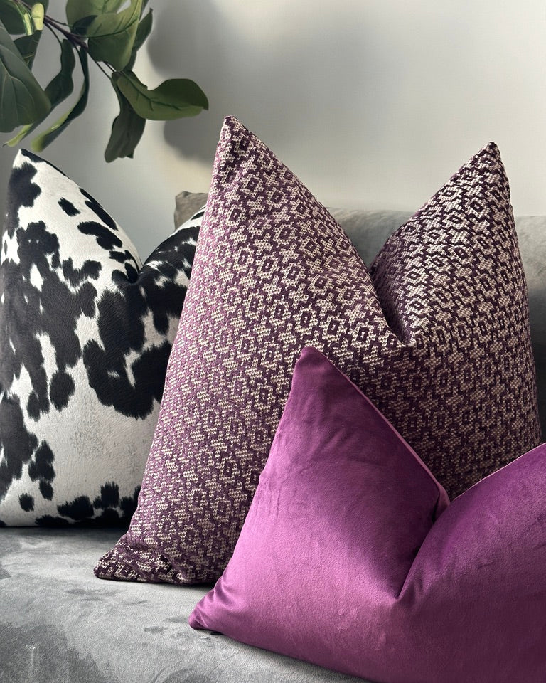 Purple, white and black pillow combination on grey sofa