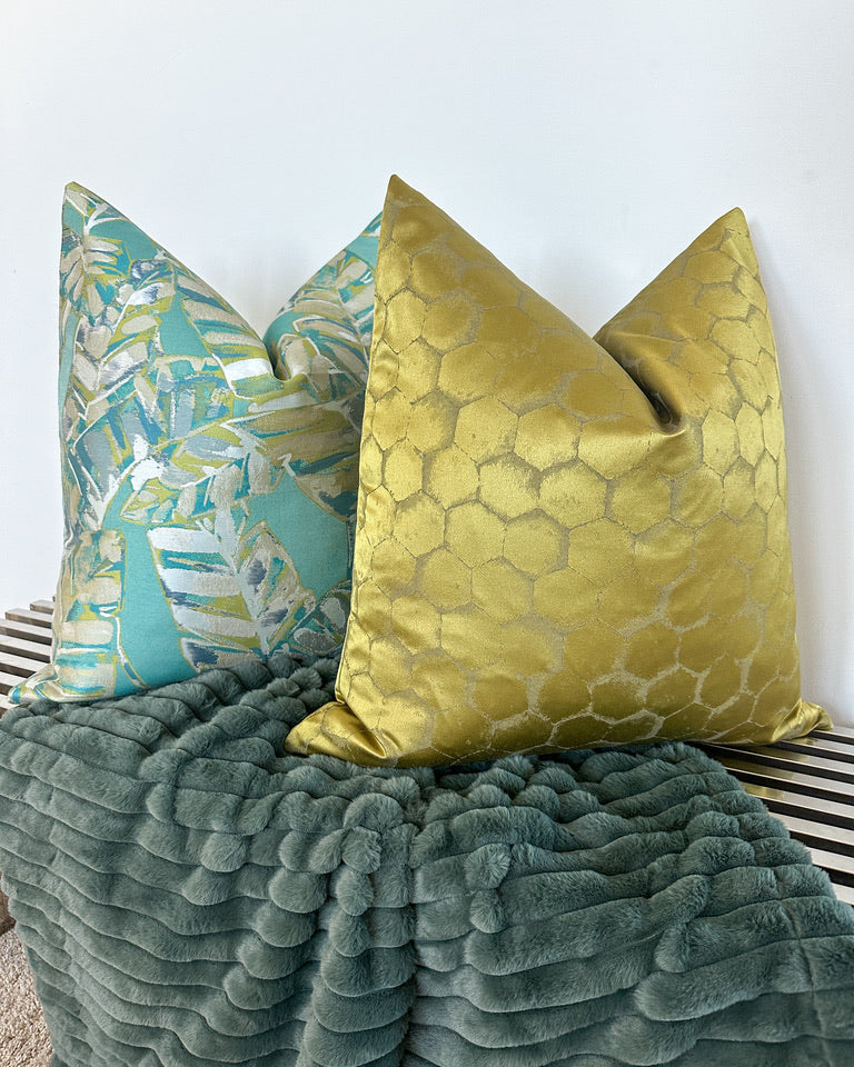Chartreuse and aqua colored pillows with faux fur throw blanket on silver bench
