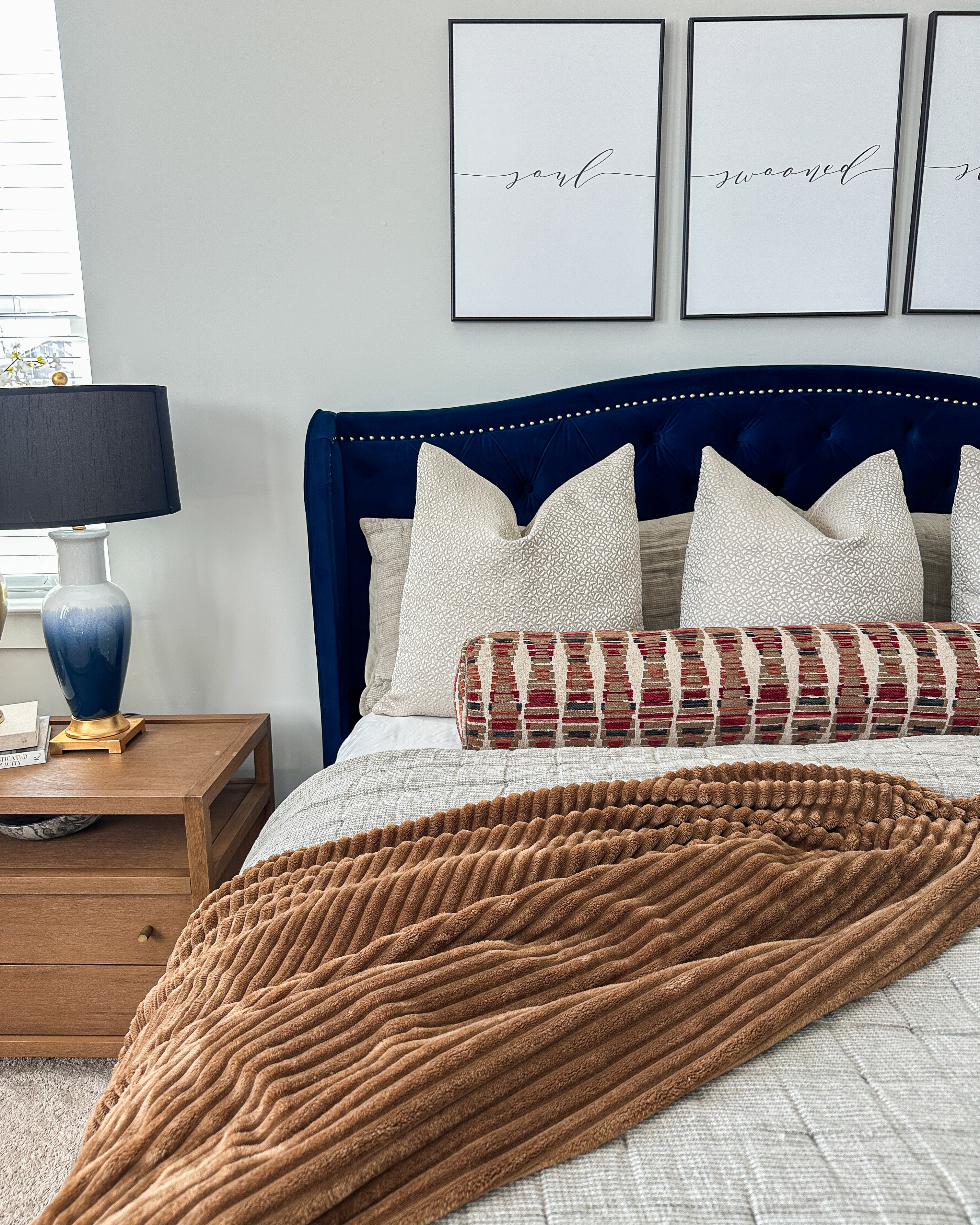 Master bedroom with navy bedframe, nightstand, and wall art