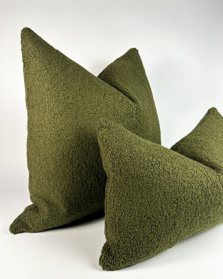 Olive green boucle pillows on a white backdrop