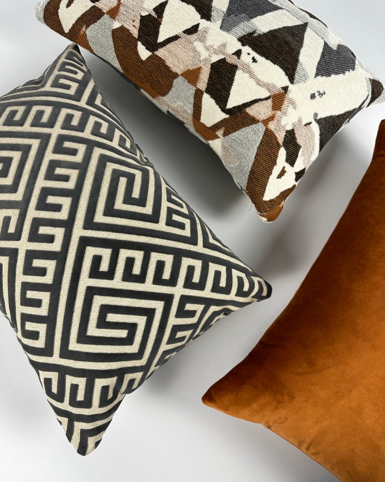 3 lumbar pillows in shades of gray and camel laid on a white backdrop