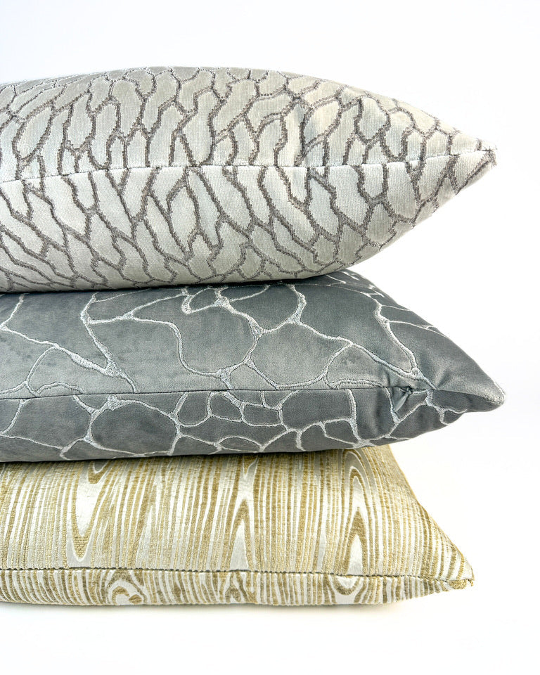 Metallic, patterned pillow covers in ivory, silver, and gold colors on white backdrop