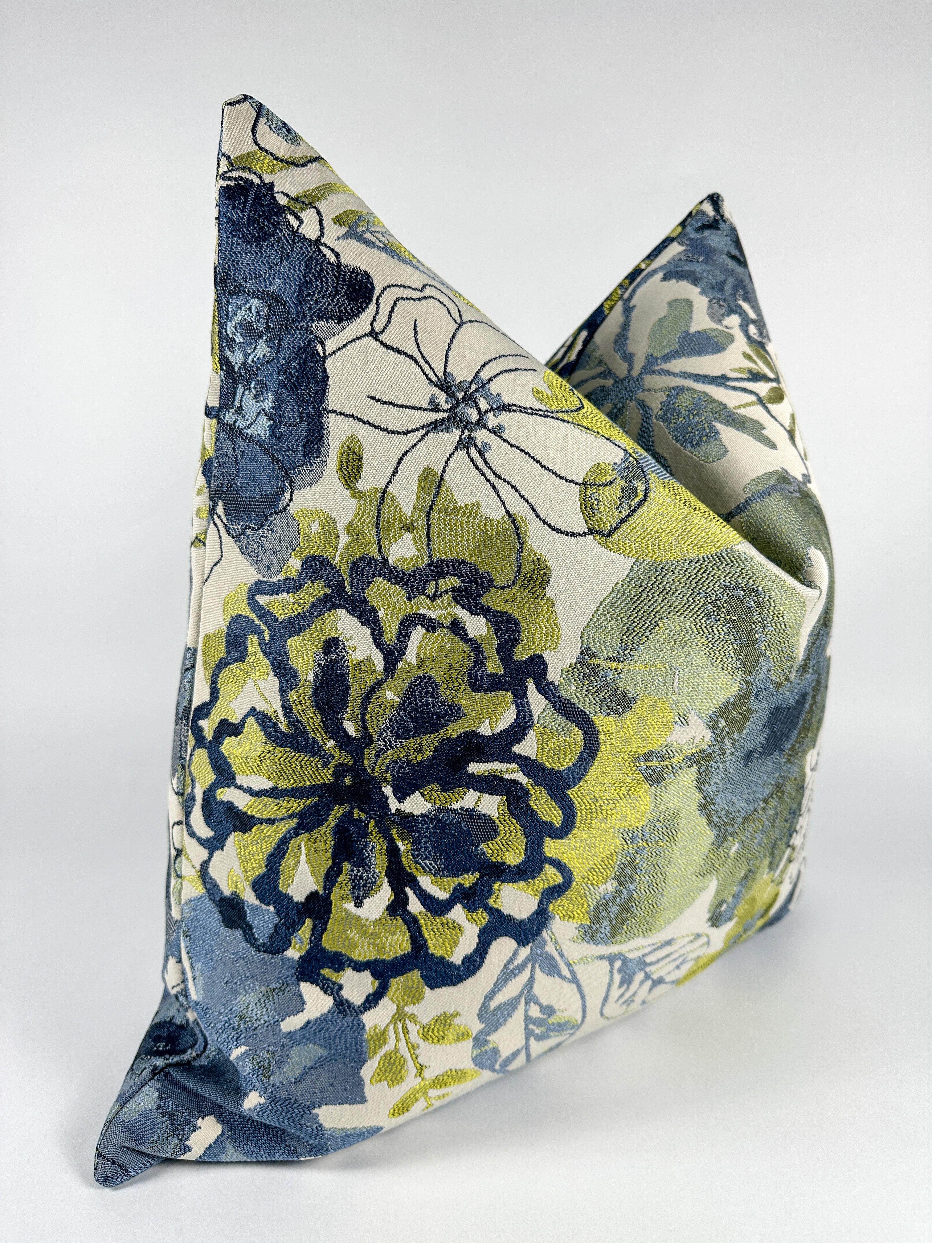 A triangular-shaped pillow cover with a floral pattern in blue and green shades.