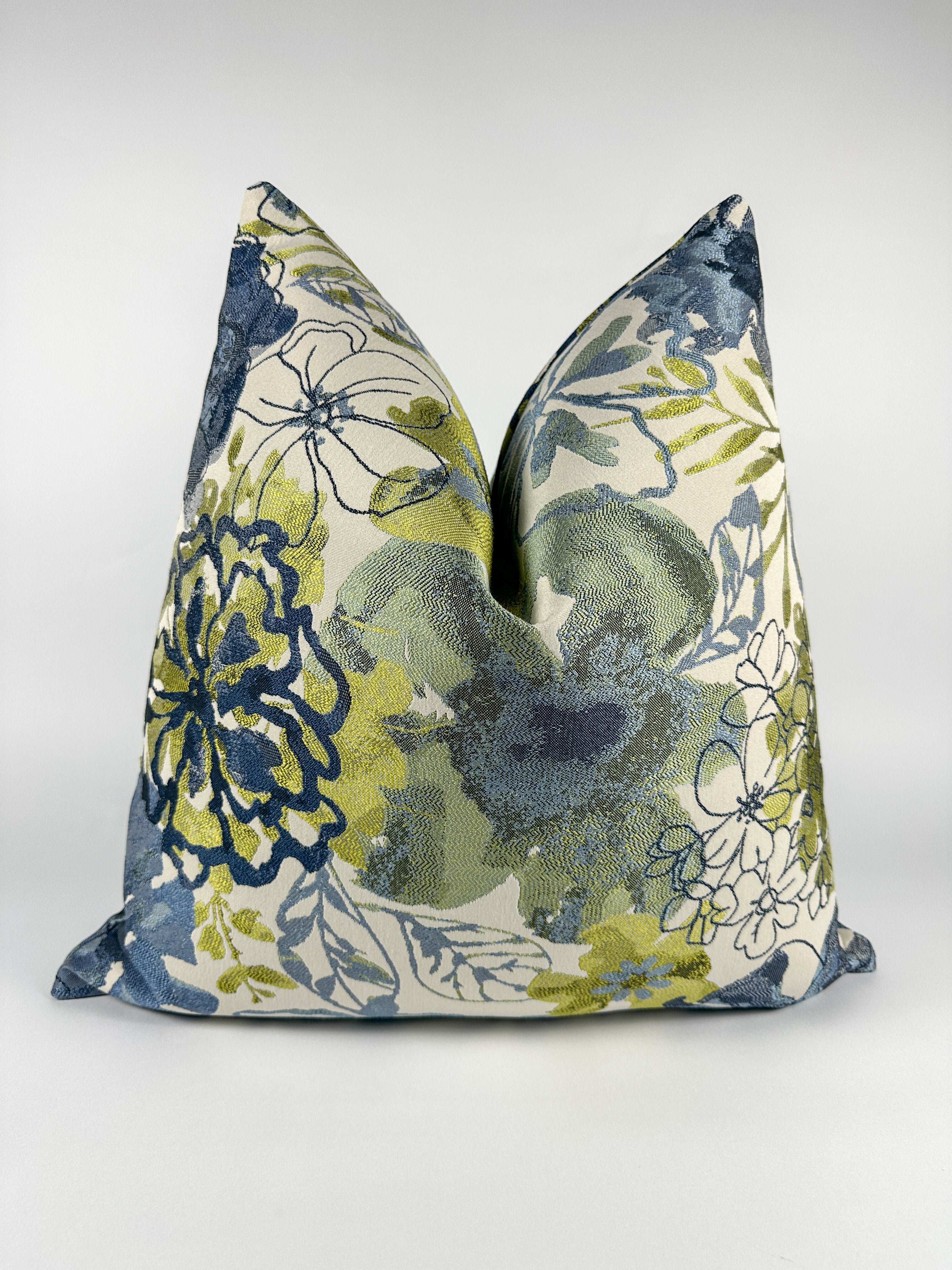 A triangular-shaped pillow cover with a floral pattern in blue and green shades.